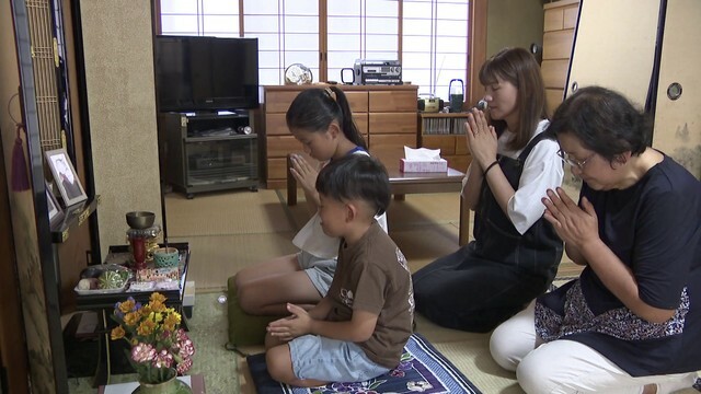 仏壇に手を合わせる三井さん家族