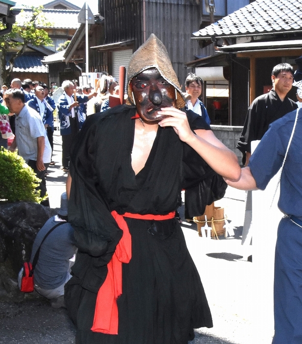 神棒を右手に携え女性の姿を探す八朔祭の天狗＝2017年撮影