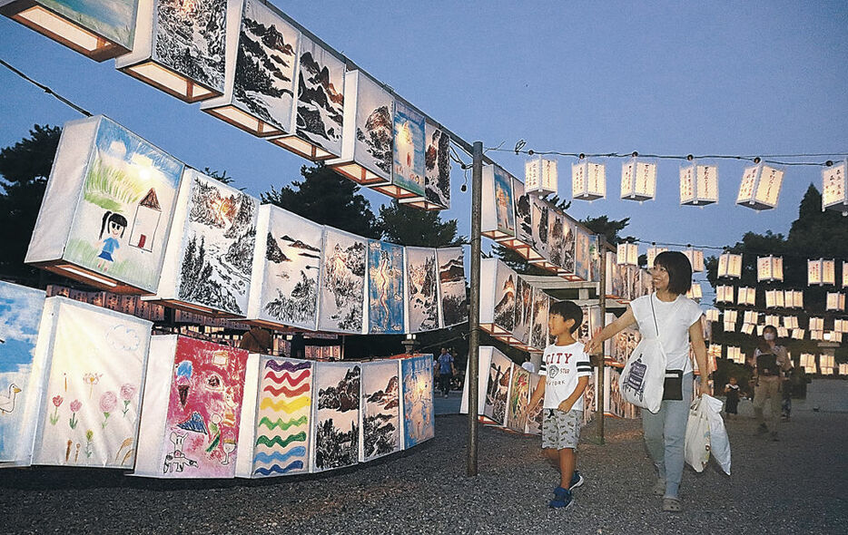 明かりがともるあんどんを眺める参列者＝富山県護国神社