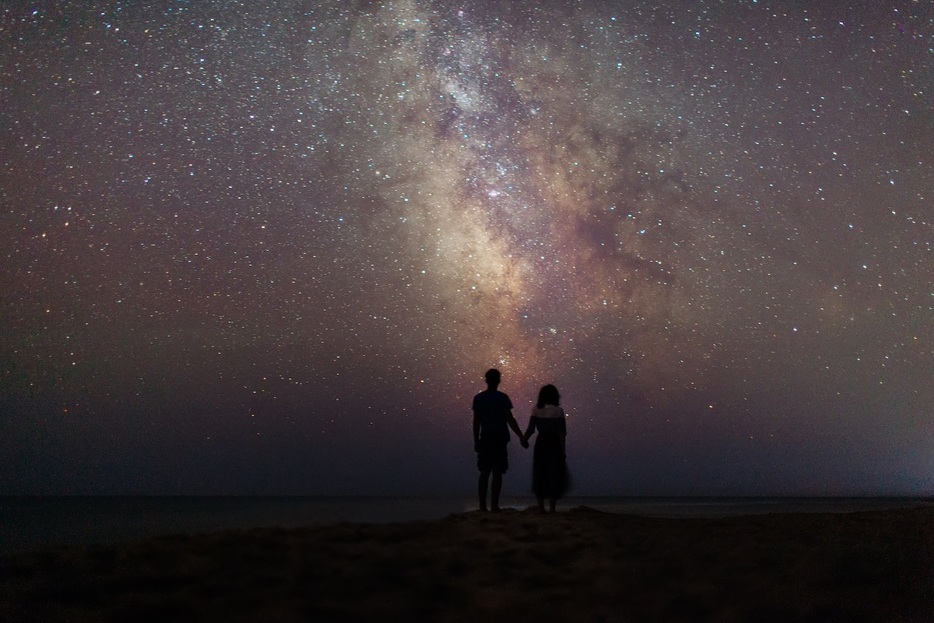 星空の下で浜辺を歩くカップル（Getty Images)