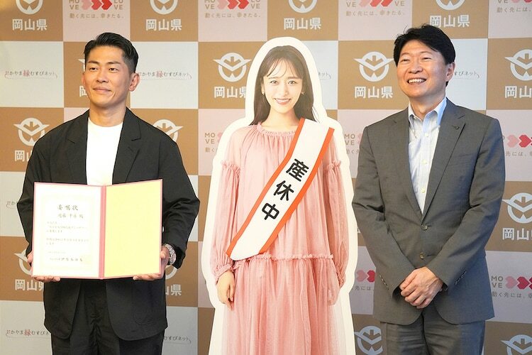 妻・近藤千尋（中央パネル）に代わり「おかやま結婚応援アンバサダー」就任式に出席したジャングルポケット太田（左）と、伊原木隆太・岡山県知事（右）。