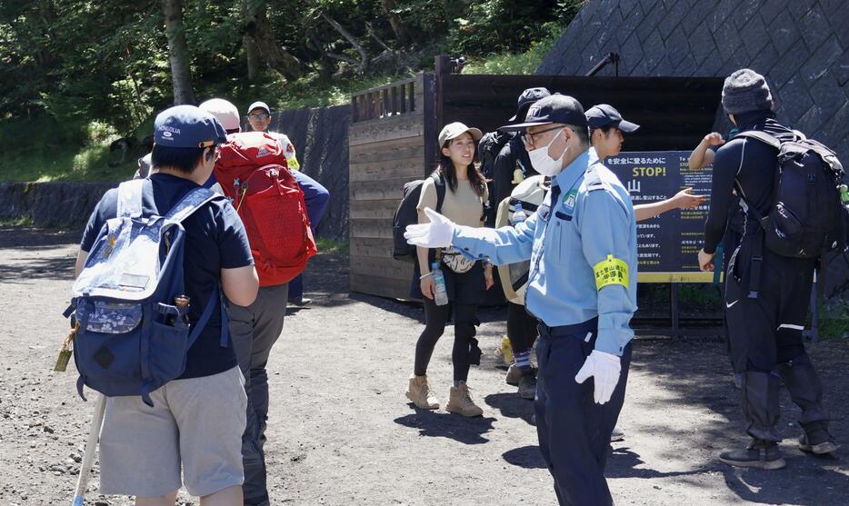 富士山の山梨県側登山道「吉田ルート」の5合目でゲートを通過する登山客（左）＝11日