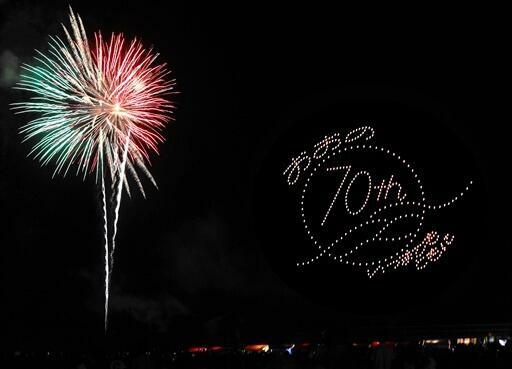 大野市制70周年記念ロゴを浮かべるドローンと打ち上げ花火の共演=8月13日、福井県大野市の真名川憩いの島