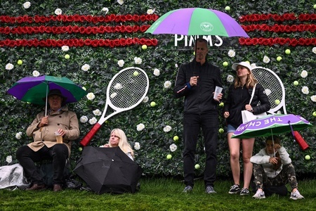 テニス、ウィンブルドン選手権。傘で雨をよけながら大型スクリーンで観戦する観客（2023年7月4日撮影）。