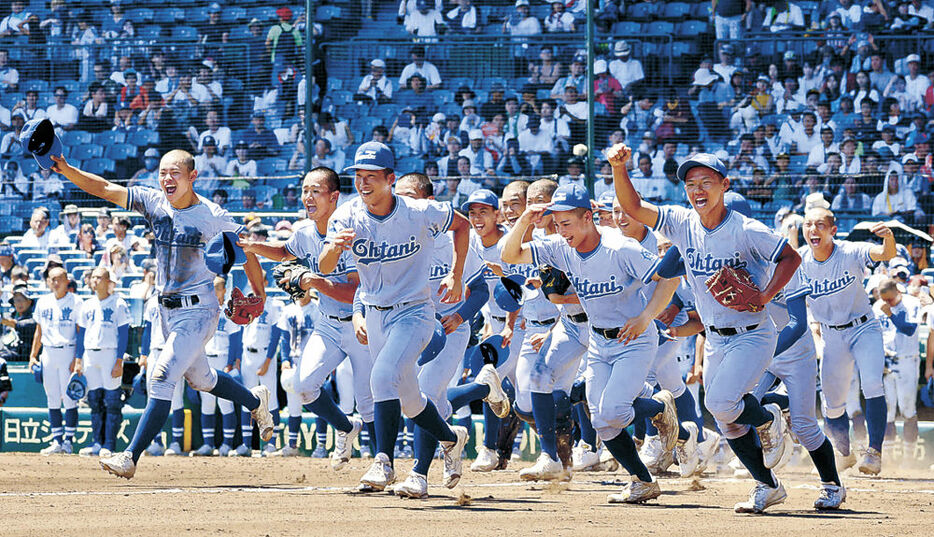 甲子園初勝利を収め、応援団の下へ走り出す小松大谷ナイン＝甲子園球場