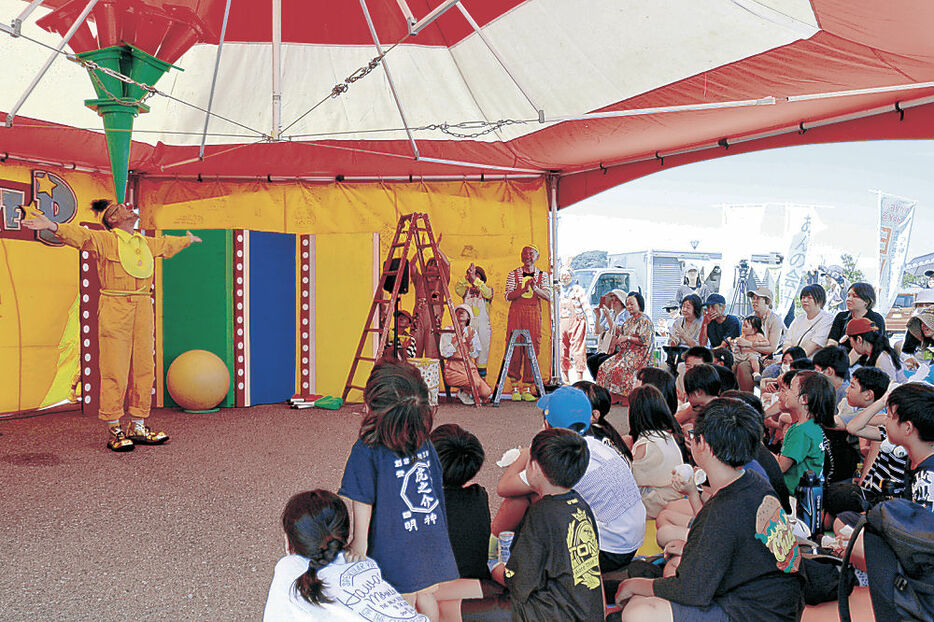 クラウンの曲芸に見入る来場者＝輪島市の輪島キリコ会館駐車場