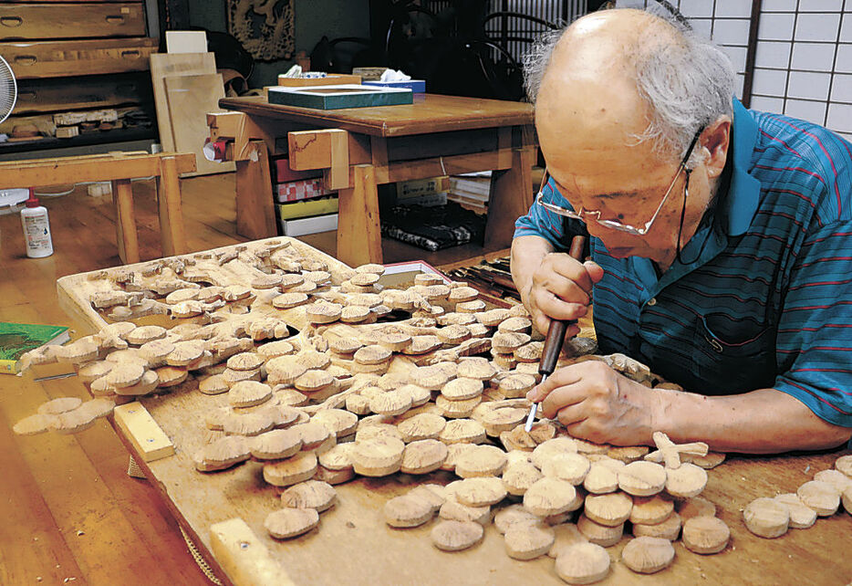 彫刻師が仕上げる井波彫刻。大阪・関西万博会場で作品が展示される＝７月、南砺市井波