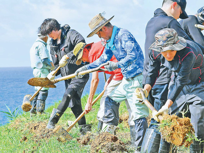 7人と一緒にあぜの修復を進める白尾友一さん（左から4人目）