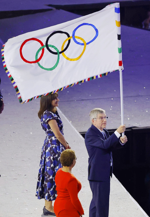 パリ五輪閉会式で五輪旗を振るIOCのバッハ会長＝11日、パリ郊外