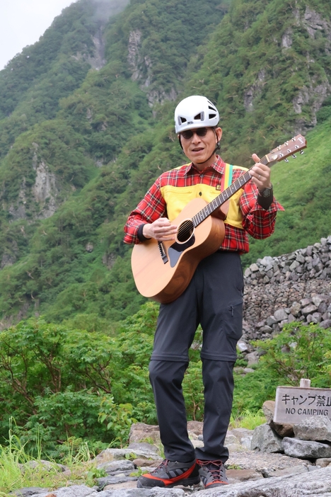 登山者を前に「命の道しるべ」を歌う中山次長