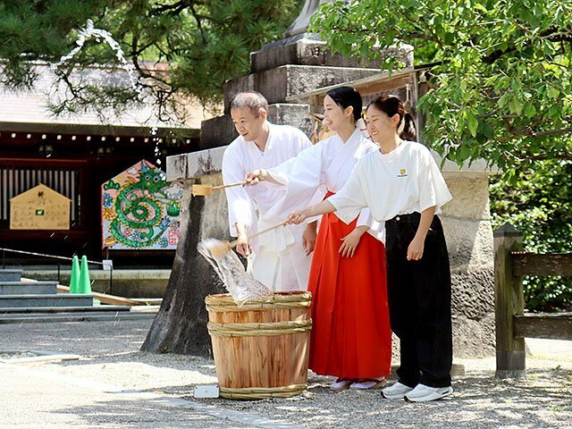 勢いよく水をまく巫女ら