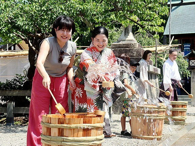 ひしゃくで水をまき涼しさを味わう参拝者ら