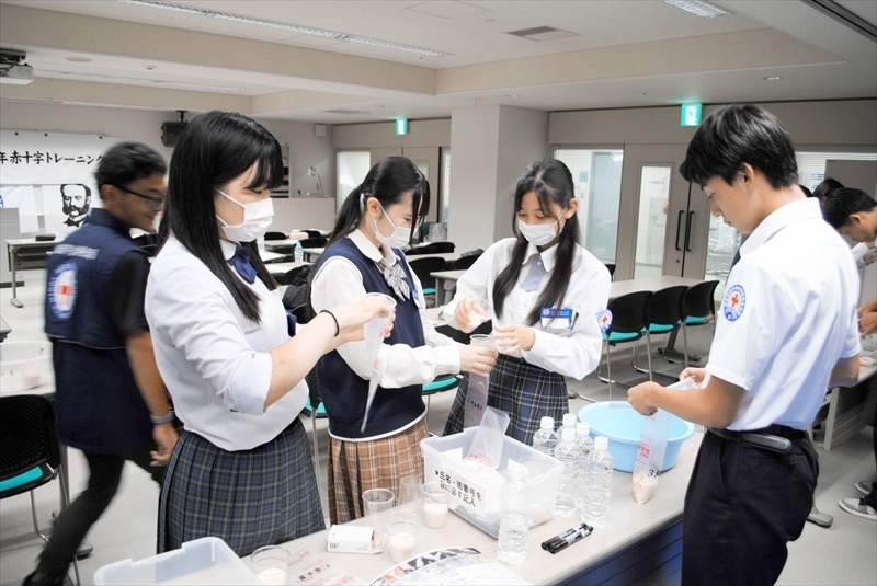 災害用非常食炊飯袋にコメと水を詰める高校生