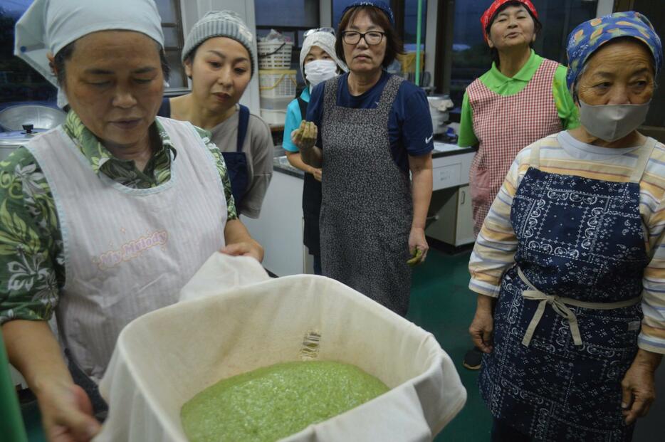 講師の新城さん（前列左）のフーチバームッチー作りに見入る大宜味村婦人連合会の会員ら＝7月23日、大宜味村喜如嘉の村農村環境改善センター