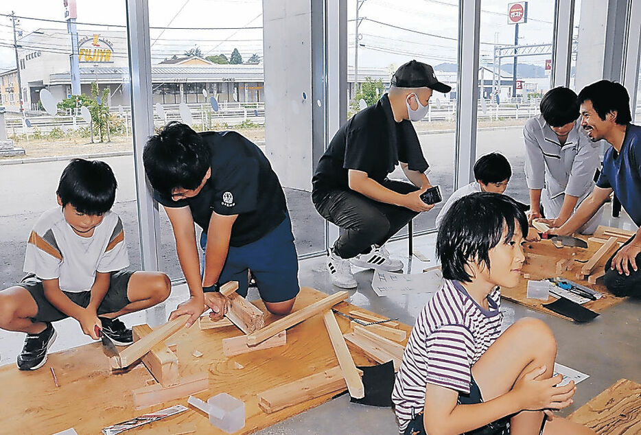 のこぎりで木を切る参加者＝氷見市芸術文化館