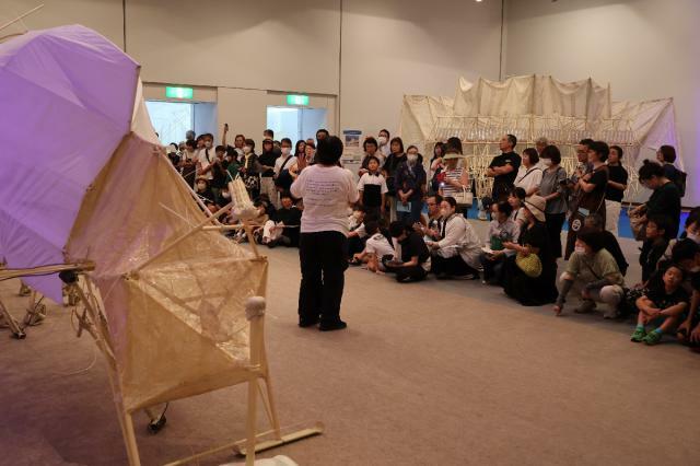 テオ・ヤンセンさんの作品の解説を聴く来場者ら＝２１日午後、宮崎市・県立美術館