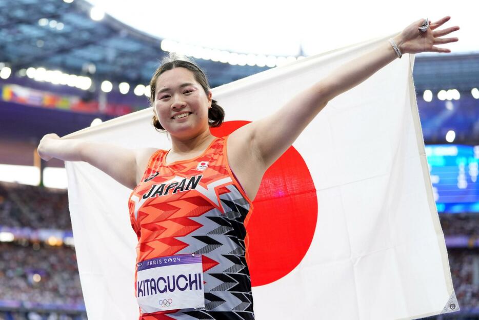 パリ五輪の陸上女子やり投げで金メダルを獲得し、日の丸を掲げる北口榛花＝10日、パリ郊外（共同）