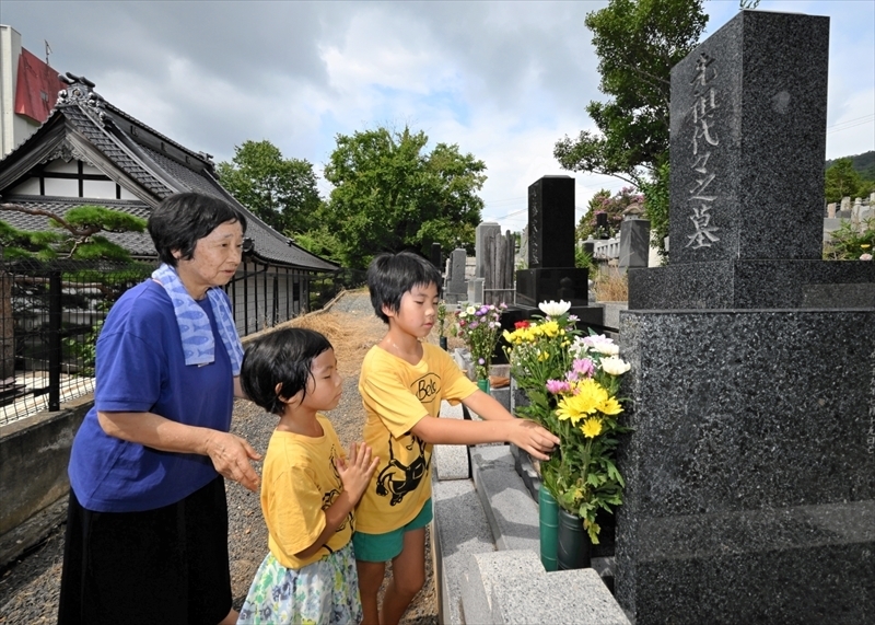 墓前に花を供える家族＝１３日午前、福島市・大明神墓地