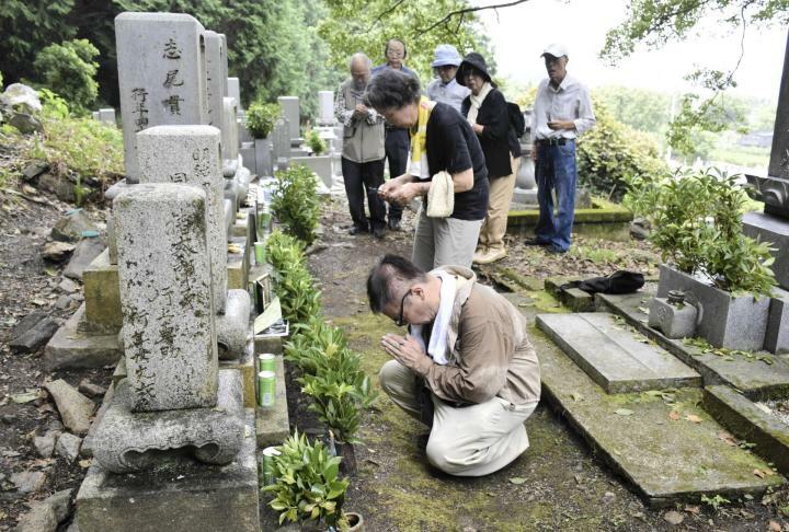 125年前の別子大水害で亡くなった祖先の墓前で合掌する志尾さん（手前）ら