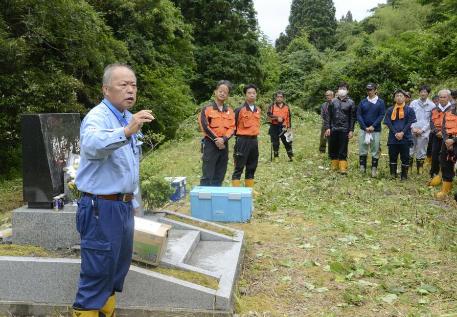 旧国鉄の能登線で起きた脱線事故の「語り部」として、慰霊碑の前でJR社員らに当時の体験を話す須鹿渉さん＝6月、石川県穴水町