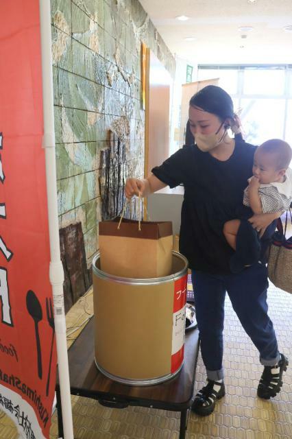 串間市役所に設置されたフードポストに、家庭で余った食料品などを寄付する親子連れ