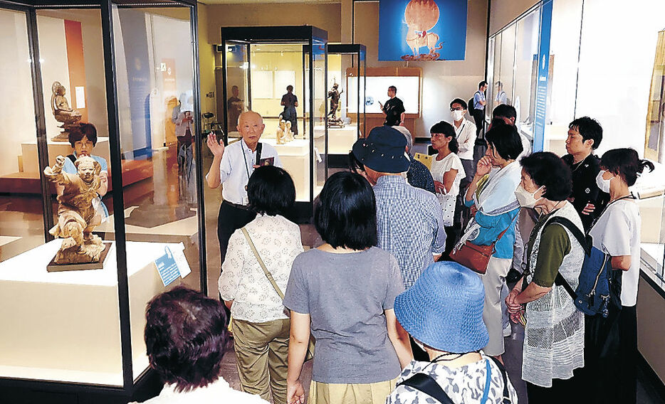 作品解説を楽しみながら「伽藍神立像」（左）などを鑑賞する来場者＝金沢市の石川県立美術館