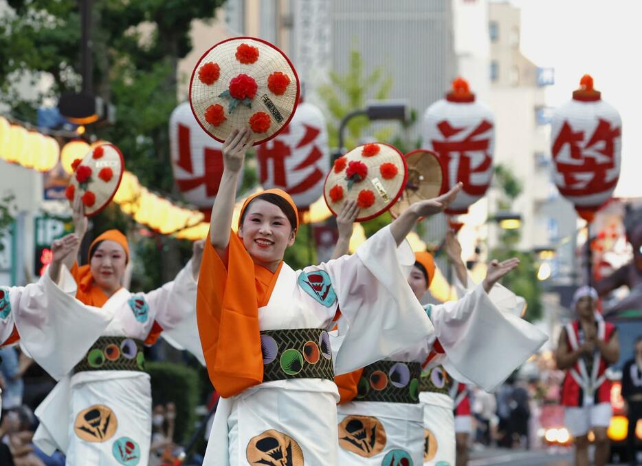 「山形花笠まつり」で紅花をあしらった花笠を手に舞を披露する踊り手＝5日夕、山形市