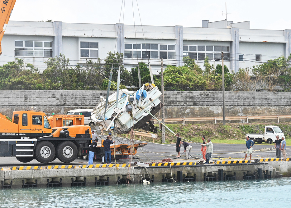 転覆した漁船の引き揚げ作業を行う住民たち＝29日、鹿児島県喜界町小野津漁港