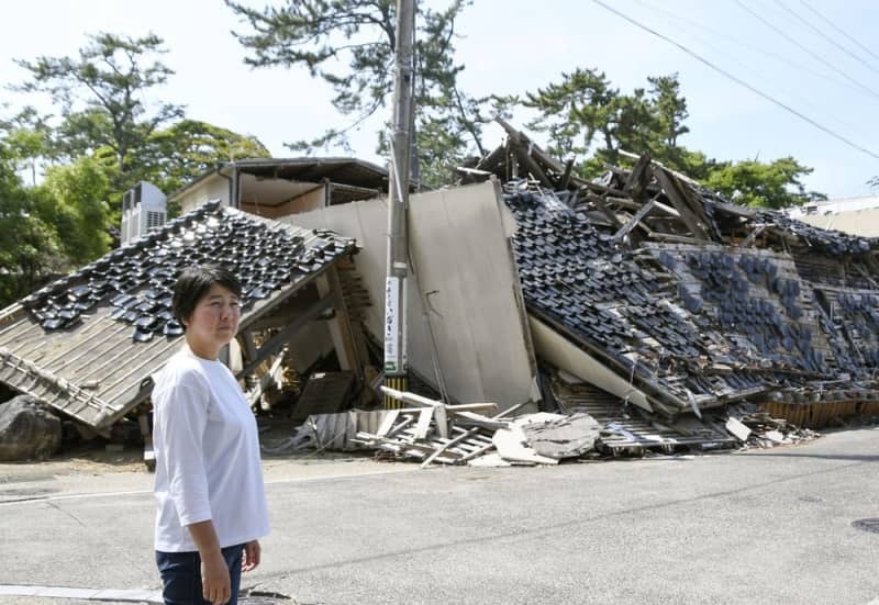 能登半島地震で倒壊した重蔵神社の前に立つ禰宜の能門亜由子さん＝２０２４年６月１２日、石川県輪島市