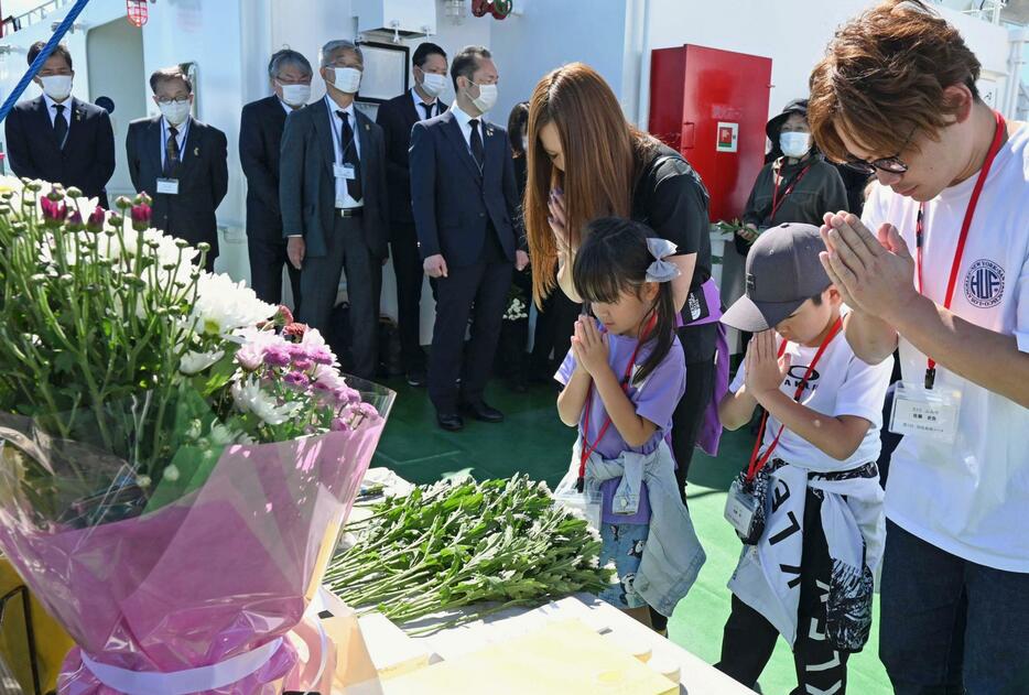 先祖を弔う洋上慰霊の慰霊式で手を合わせる家族＝20日午後、北海道羅臼町沖（代表撮影）