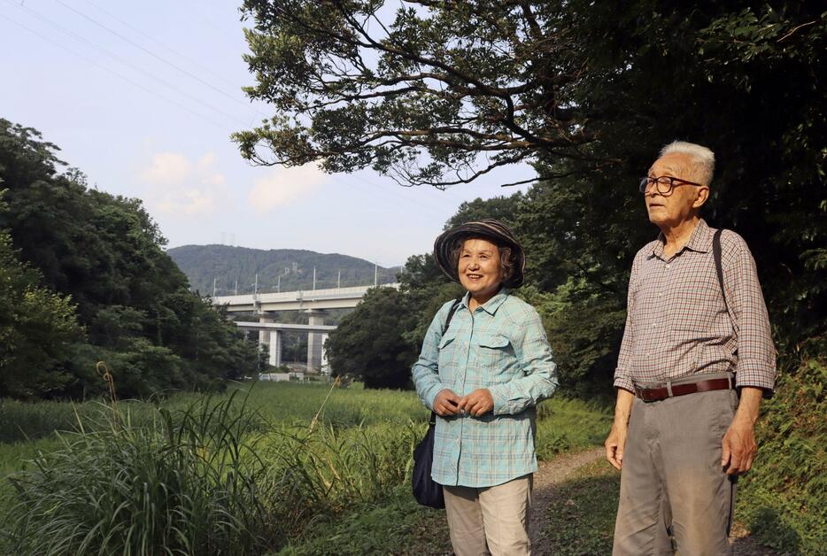 「中池見湿地」を歩く笹木智恵子さん（左）と進さん。奥は3月に延伸開業した北陸新幹線の高架＝2024年7月23日、福井県敦賀市