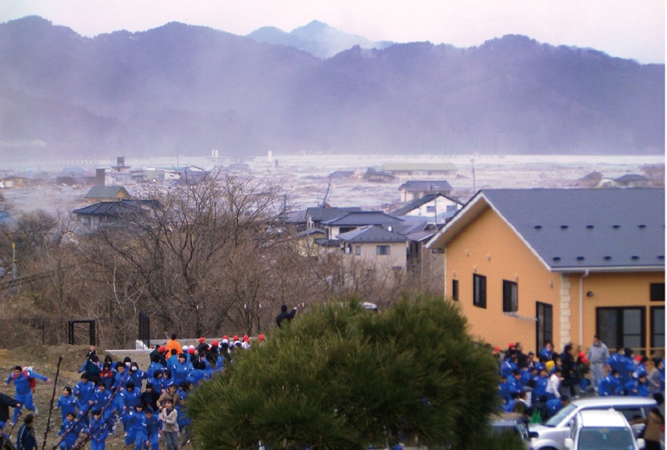 津波を見て、高台へと非難する小中学生たち（国土交通省東北地方整備局HPより）