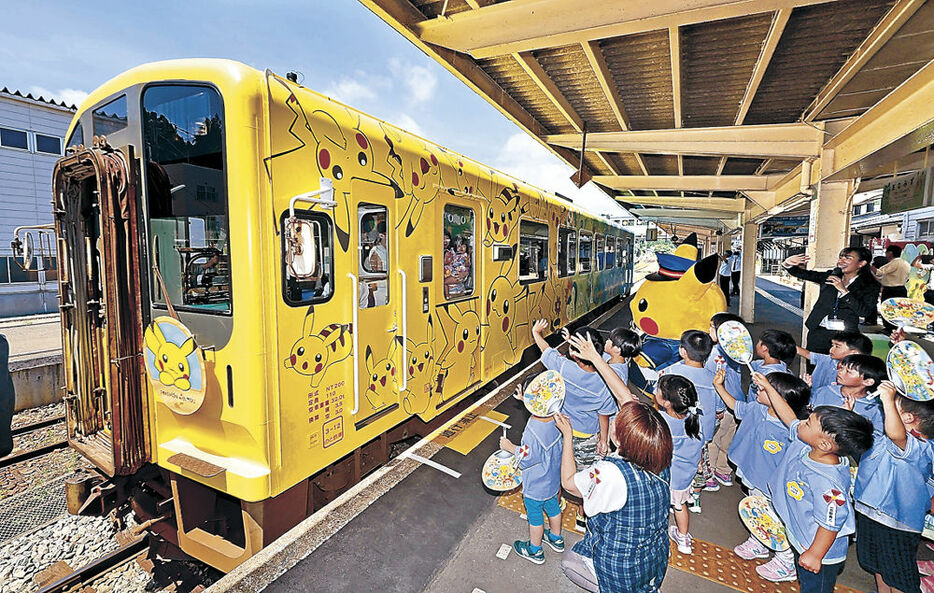 出発するラッピング列車を見送る園児とピカチュウ＝１日午前１０時５１分、のと鉄道穴水駅