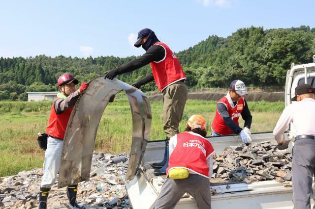 搬入された災害ごみを荷下ろしするＮＰＯ法人「日本九援隊」のメンバーら＝１１日午前、日南市南郷町・黒潮環境センター