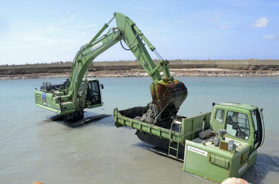 能登半島地震で海底が隆起した石川県輪島市の赤神漁港で、土砂をさらう「しゅんせつ」作業を行う水陸両用のショベルカー（左）とダンプカー＝5日