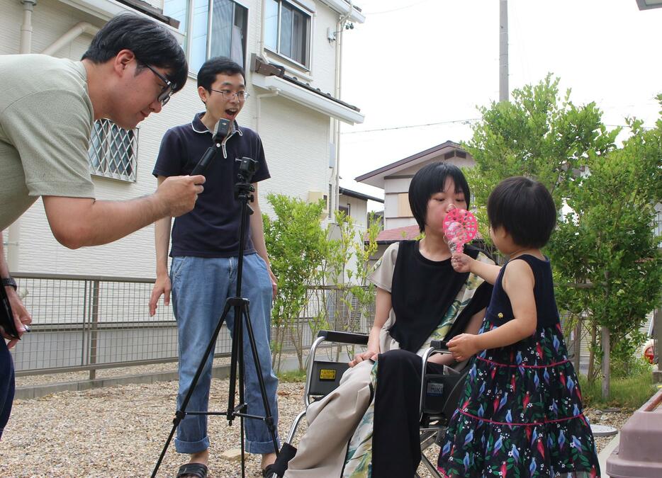 ALSを患う女性（中央右）とその家族を撮影する吉村大作さん（左）＝2024年6月、愛知県