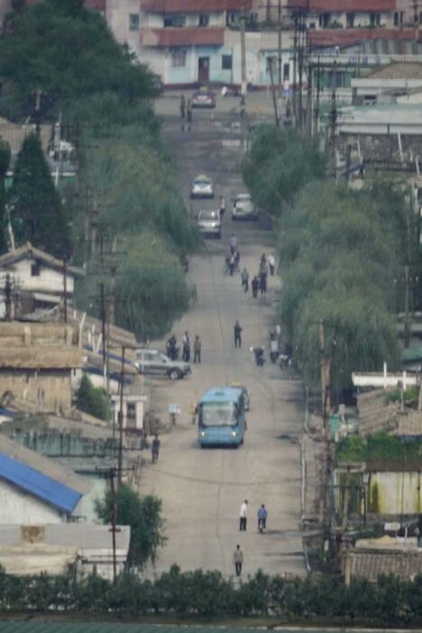 人や車が行き交う北朝鮮北西部新義州の中心部＝2日、中国・丹東から撮影（共同）