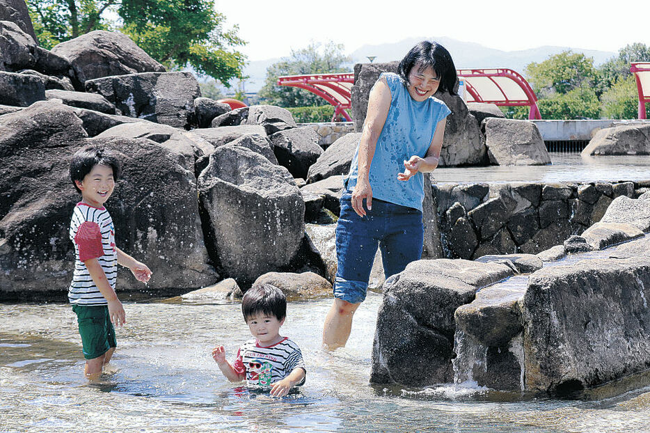 ３７．２度を記録した富山空港近くのとやま健康パークの「じゃぶじゃぶ池」で水遊びする親子＝２３日午後０時１０分