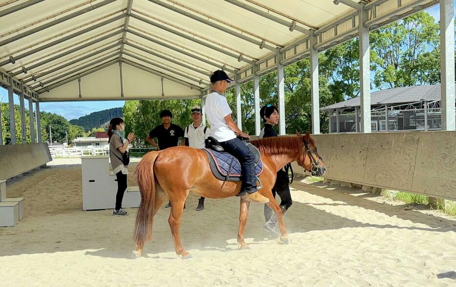 　乗馬体験する参加者と馬を引く小崎