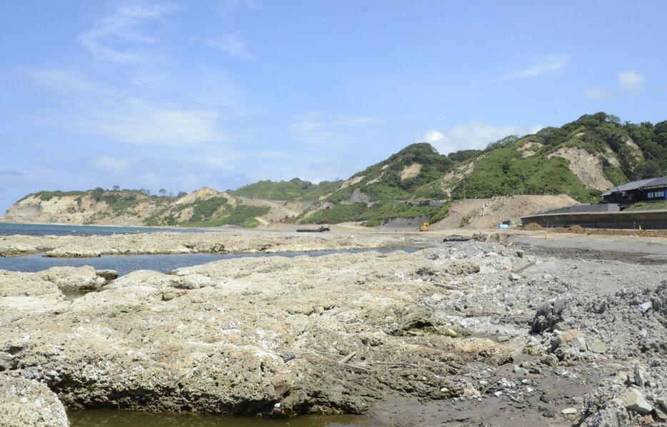 能登半島地震で隆起した石川県輪島市の海岸。奥は大規模な土砂崩落現場＝8月