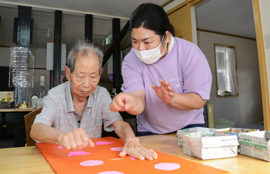 中国帰国者家族の利用者と指を使ったゲームをする石井さん