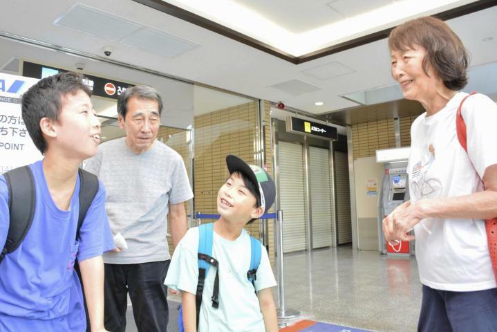 松山空港で孫たちとの再会を喜ぶ夫婦＝10日午後、松山市南吉田町