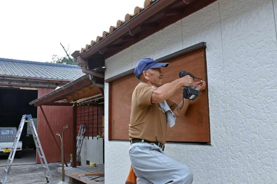 台風接近に備え、窓枠に板を取り付ける住民＝２６日、龍郷町赤尾木