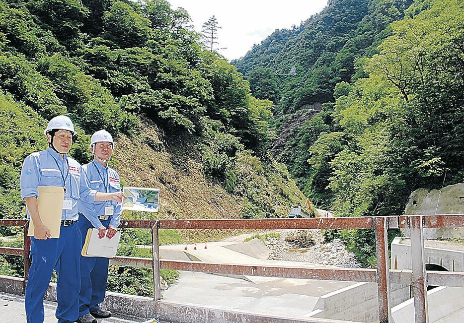 利賀ダムの本体工事を説明する職員。前方の谷に本体を構築する＝南砺市利賀地区