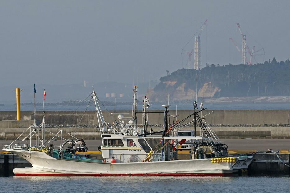 福島県浪江町の請戸漁港に停泊する漁船。奥は東京電力福島第1原発の排気筒＝24日午前