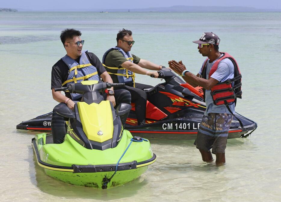 サイパン島の中心街ガラパンのビーチで水上バイクの指導を受けるマレーシア人観光客＝2024年6月（共同）