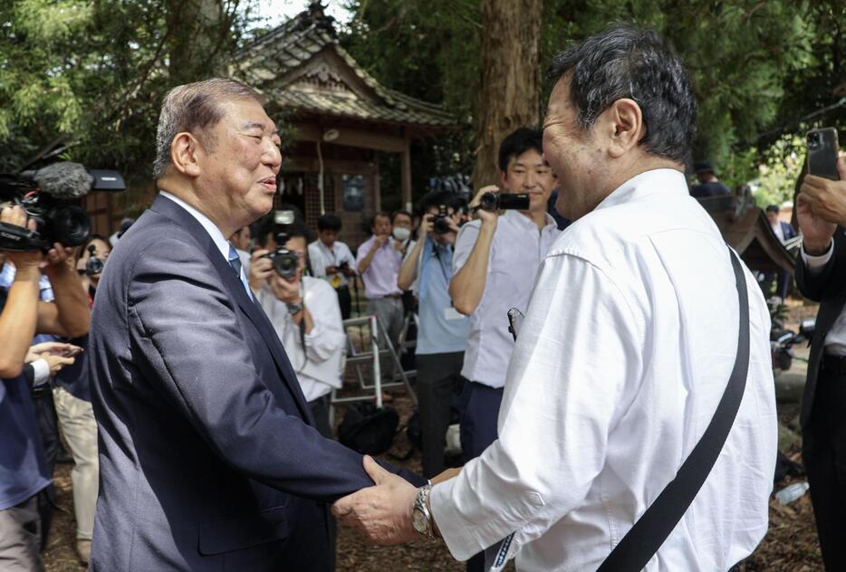 自民党総裁選への出馬表明の会場で、支持者と握手する石破元幹事長（左）＝24日午前、鳥取県八頭町