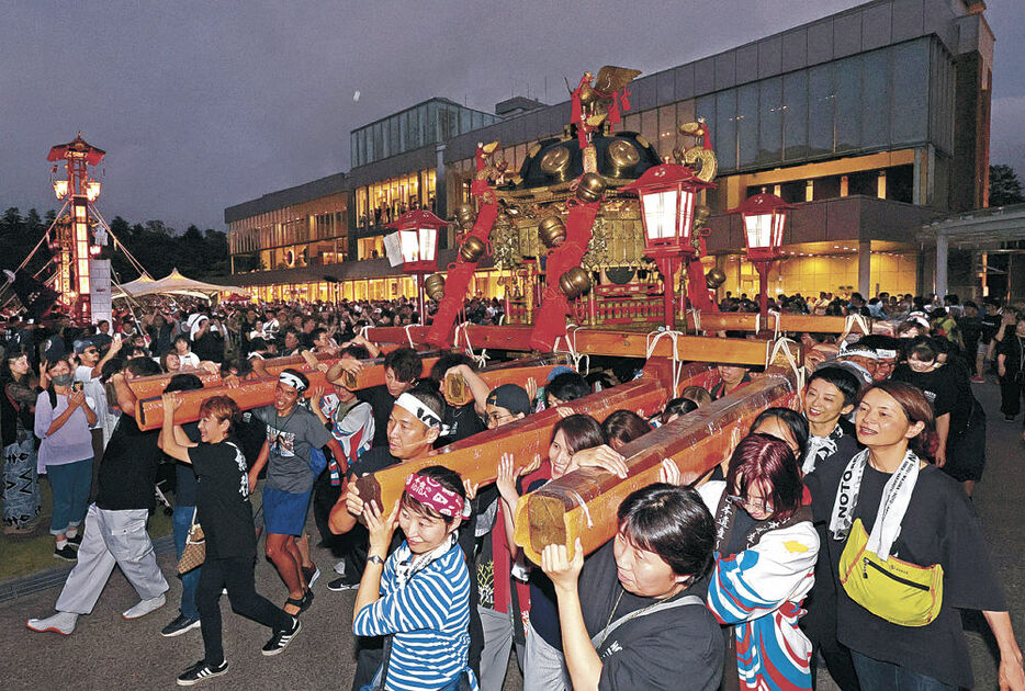 能登復興を祈願して巡行する重蔵神社のみこしと能登のキリコ＝１７日午後７時、金沢市のしいのき緑地周辺