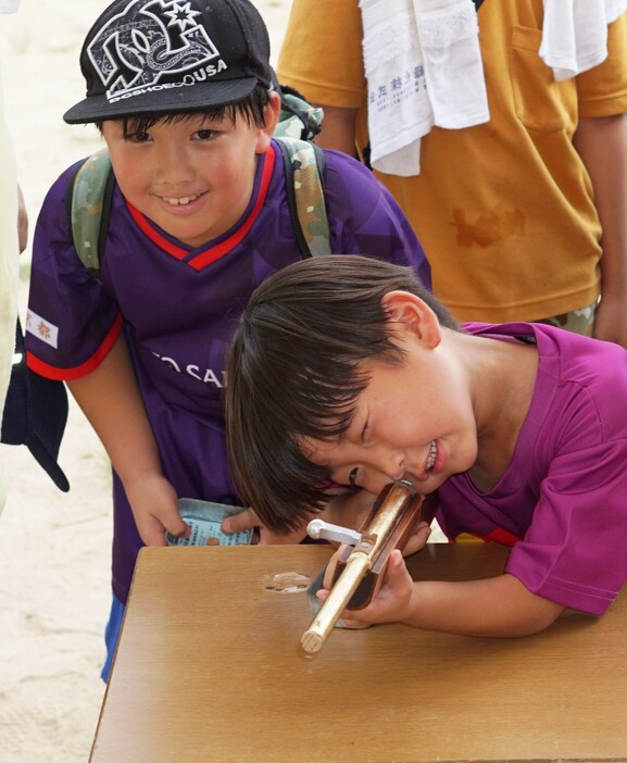 射的で狙いを定める子ども