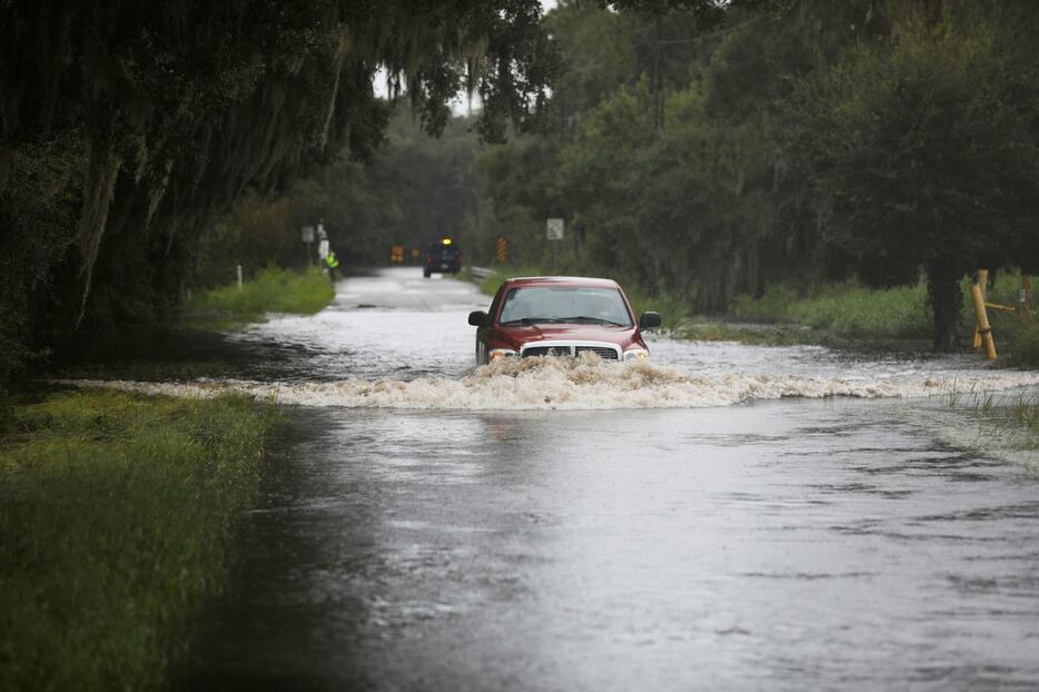 5日、米南部フロリダ州でハリケーン「デビー」上陸後、冠水した道路を走行するトラック（ロイター＝共同）